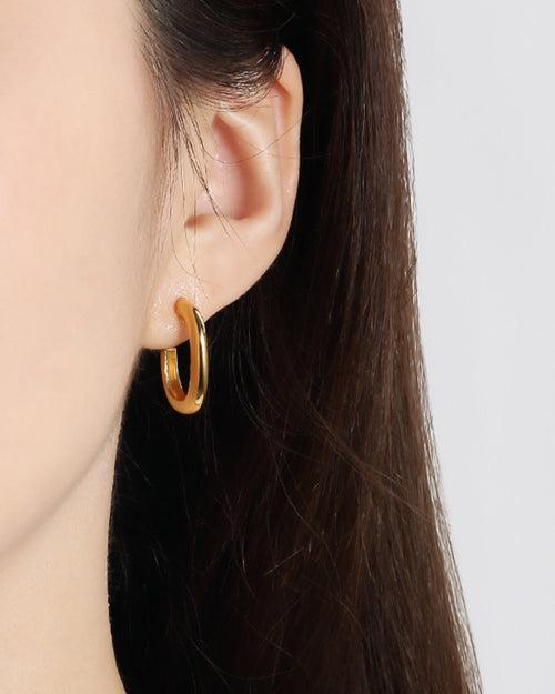 Small gold huggie earrings worn on ear modern minimalist everyday gold jewelry