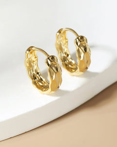 organic molten gold huggie earrings on neutral background modern jewelry