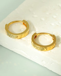 Small gold huggie hoop earrings textured detail angle view