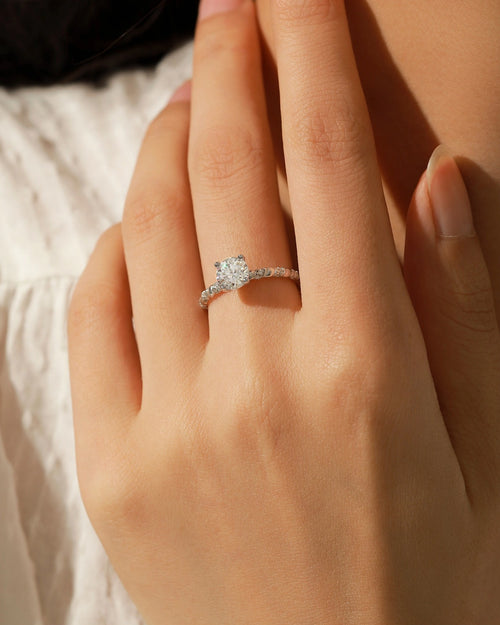 Hand wearing elegant twisted solitaire moissanite ring