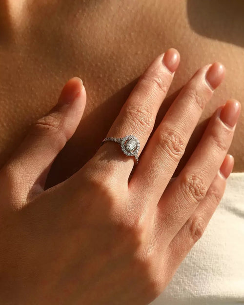 Oval halo moissanite ring worn on hand in sunlight