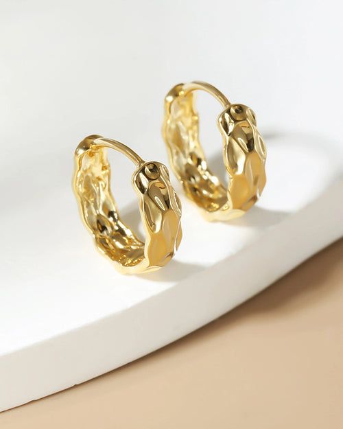 organic molten gold huggie earrings on neutral background modern jewelry