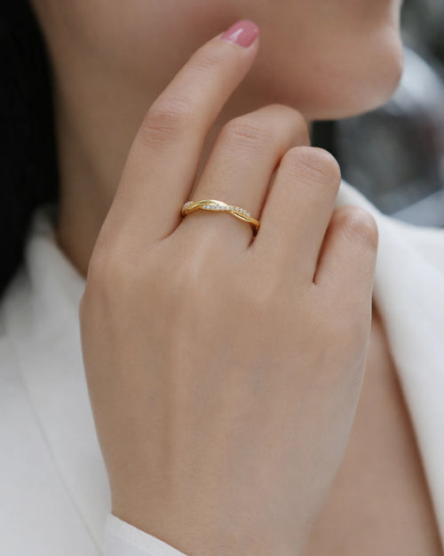 Woman wearing 18k gold twisted moissanite ring on ring finger, minimalist fine jewelry