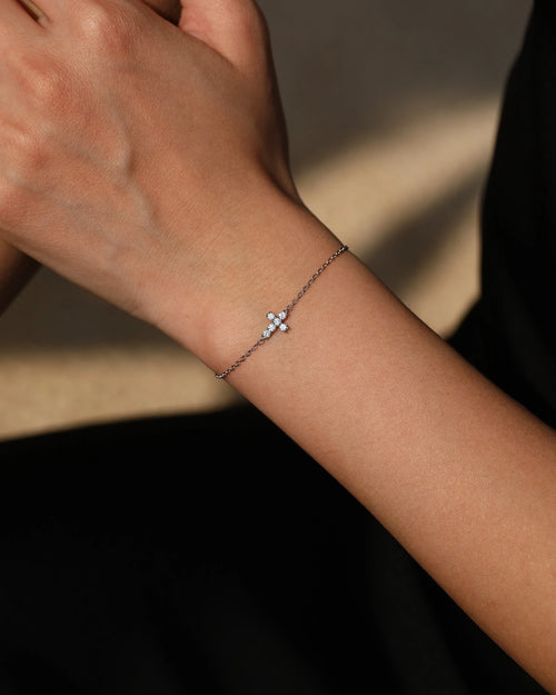 Model wearing dainty cross moissanite bracelet on wrist