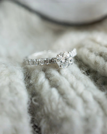 Woman holding a dried flower wearing a rose-gold halo solitaire ring – AriaEcho Jewelry
